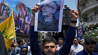 متظاهر إيراني يحمل ملصقًا لرئيس الأركان العامة للقوات المسلحة محمد باقري، الذي قُتل في غارة إسرائيلية، إيران، الجمعة 13 يونيو 2025.  