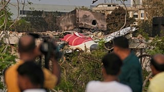 Θεατές παρακολουθούν τα συντρίμμια από τη συντριβή του αεροσκάφους της Air India την Πέμπτη που βρίσκεται στην κορυφή ενός κτιρίου στο Αχμενταμπάντ της Ινδίας, Σάββατο 14 Ιουνίου 2025.