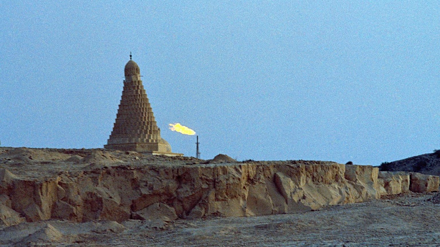 مسجد قديم وشعلة مصنع للبتروكيماويات يحرقان نواتج الغاز غير المرغوب فيها في جزيرة خرج، إيران، يوليو 1971. 