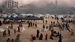 فلسطينيون يقضون وقتهم على شاطئ البحر بجوار مخيم في ميناء مدينة غزة، الجمعة 13 يونيو 2025. 