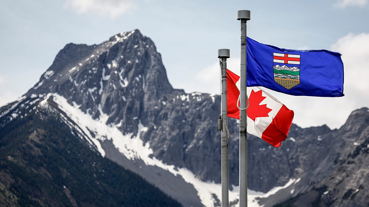 Bir Kanada bayrağı, solda, ve bir Alberta bayrağı, arka planda Wedge Dağı ile birlikte Kananaskis, Alberta'da G7 Liderler toplantısının yapıldığı yerde rüzgarda dalgalanıyor, 2 Haziran 2025.
