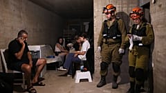 Жители и силы безопасности находятся в убежище в жилом районе, который подвергся удару иранской ракеты в центральном израильском городе Бат-Ям. 15 июня 2025 года
