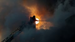 Спасатель тушит пожар на складе гуманитарной помощи, разрушенном в результате удара российского беспилотника в Запорожье, Украина, 14 июня 2025 г.