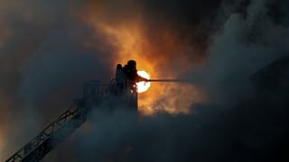 Спасатель тушит пожар на складе гуманитарной помощи, разрушенном в результате удара российского беспилотника в Запорожье, Украина, 14 июня 2025 г.