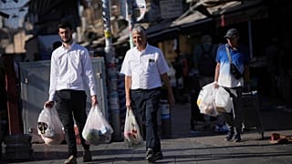 إسرائيليون يقومون بتخزين البقالة في سوق محاني يهودا في القدس قبل يوم السبت، الجمعة، 13 يونيو 2025.