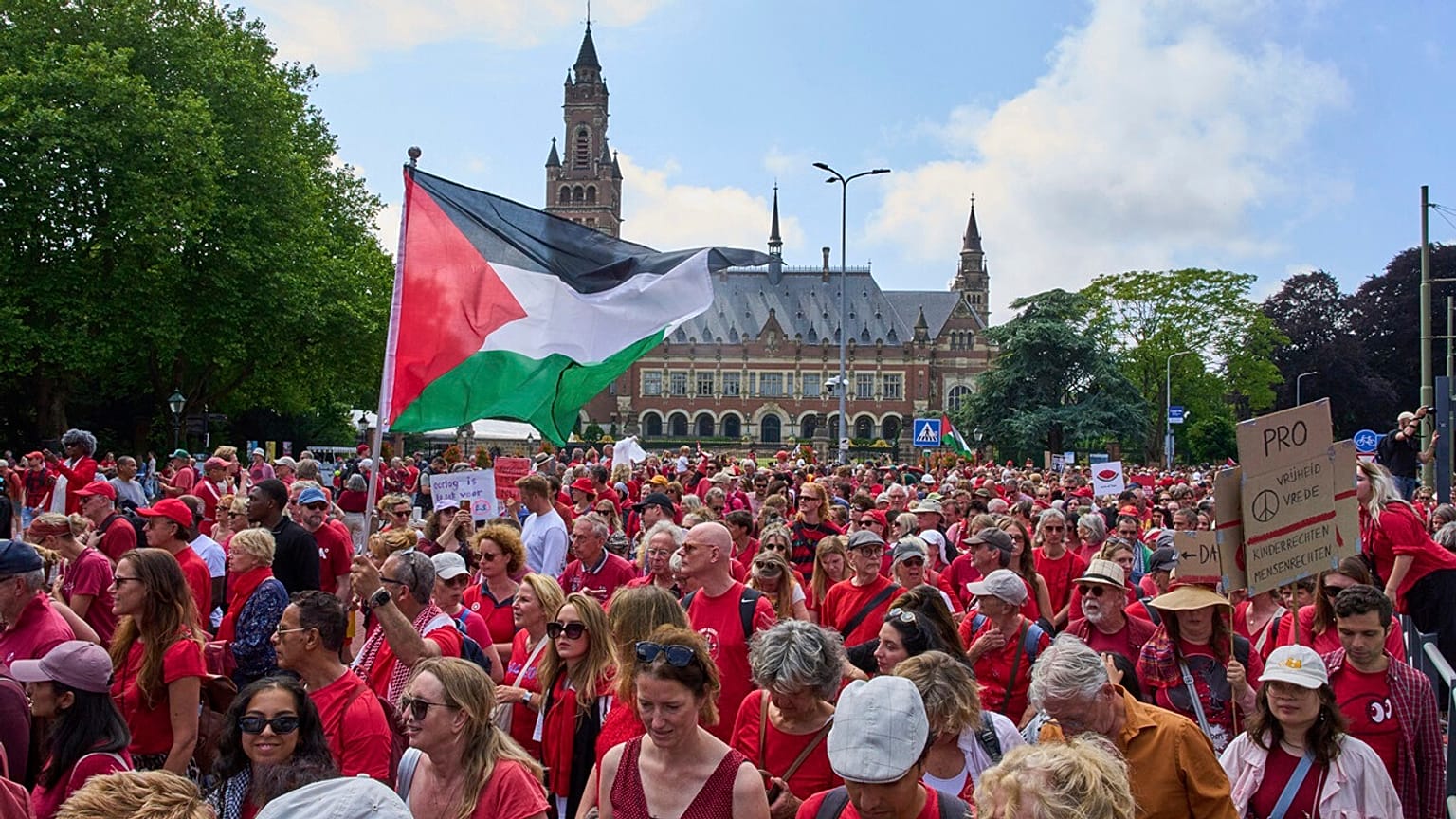 Dezenas de milhares de manifestantes vestidos de vermelho passaram pelo Palácio da Paz durante uma manifestação em Haia, Holanda, no domingo, 15 de junho de 2025.