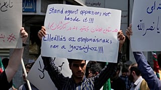 A protester holds up an anti-Israeli placard in a gathering in Tehran, Iran, Friday, June 13, 2025