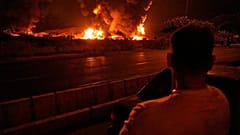 Ein Mann betrachtet die Flammen, die nach einem israelischen Angriff in Teheran, Iran, am Sonntag, 15. Juni 2025, aus einem Öllager aufsteigen.  