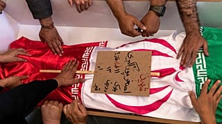 مشيعون يلمسون جثمان أصغر بوراكبري المسجى بالعلم الإيراني والذي قيل إنه قُتل خلال الغارات الإسرائيلية في مدينة تبريز شمال غرب إيران، الاثنين، 16 يونيو/حزيران 2025
