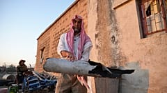 رجل سوري يحمل قطعة مدمرة يُعتقد أنها لطائرات مسيرة إيرانية أسقطتها الدفاعات الجوية الإسرائيلية في قرية جبيلية، جنوب سوريا، الجمعة 13 يونيو / حزيران 2025