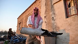 رجل سوري يحمل قطعة مدمرة يُعتقد أنها لطائرات مسيرة إيرانية أسقطتها الدفاعات الجوية الإسرائيلية في قرية جبيلية، جنوب سوريا، الجمعة 13 يونيو / حزيران 2025