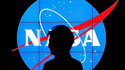 Logo NASA jest częściowo zasłonięte przez przechodzącego pieszego. 
