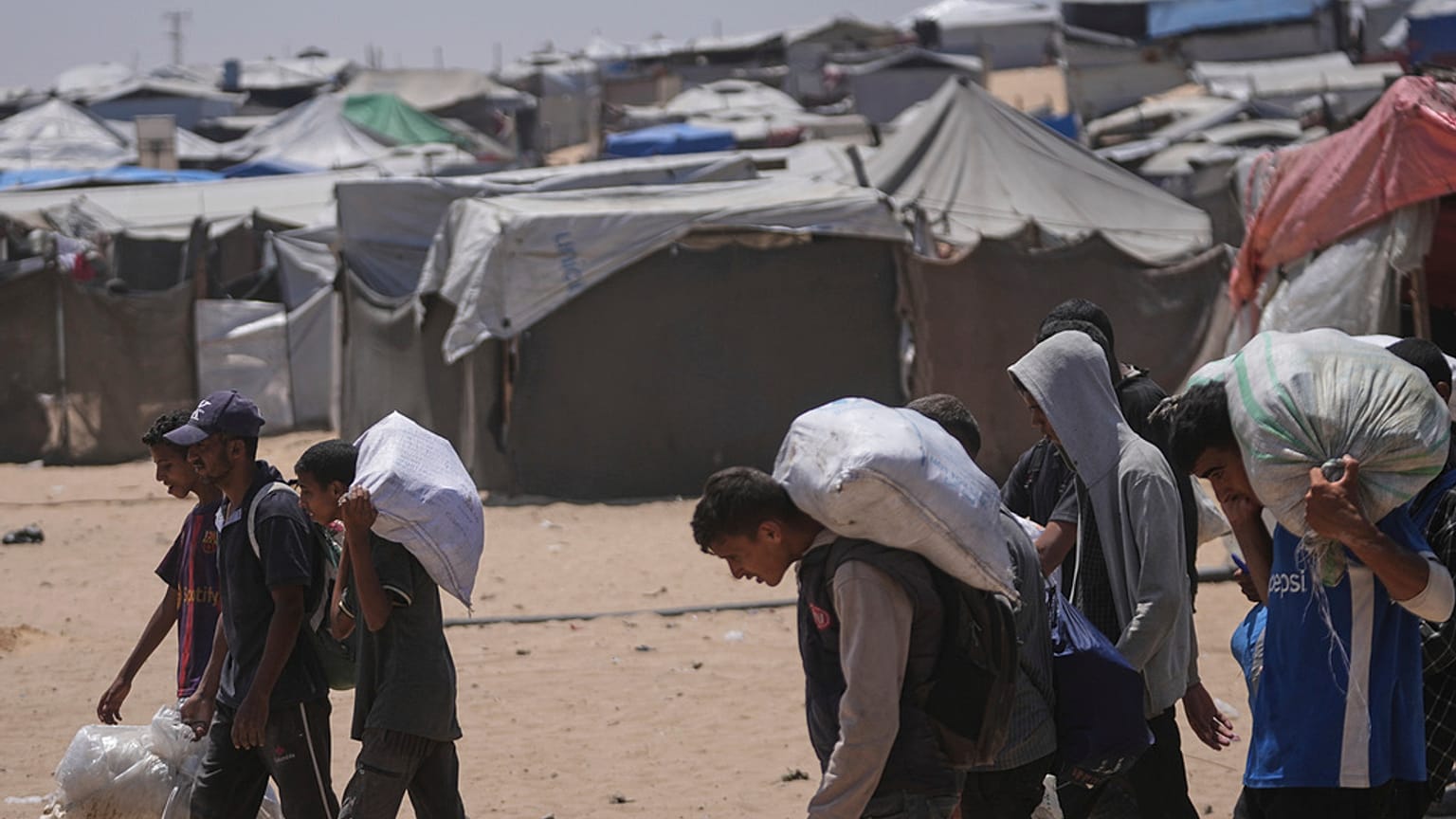 فلسطينيون يحملون أكياسًا تحتوي على مساعدات غذائية وإنسانية وزّعتها "مؤسسة غزة الإنسانية" المدعومة من الولايات المتحدة، في رفح جنوب قطاع غزة، يوم الاثنين 16 حزيران/يونيو 2025.