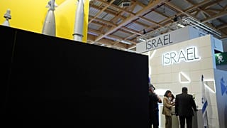 Visitatori in piedi accanto ai padiglioni israeliani bloccati da un muro nero al Paris Air Show, martedì 17 giugno 2025 a Le Bourget, a nord di Parigi.