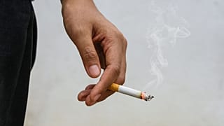 Uma mulher segura um cigarro.