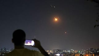 رجل يلتقط صورة لهاتف محمول بينما صواريخ تطلق من إيران باتجاه إسرائيل تحلق فوق الأراضي السورية في دمشق ، سوريا ، في وقت مبكر من يوم الأربعاء ، 18 يونيو ، 2025