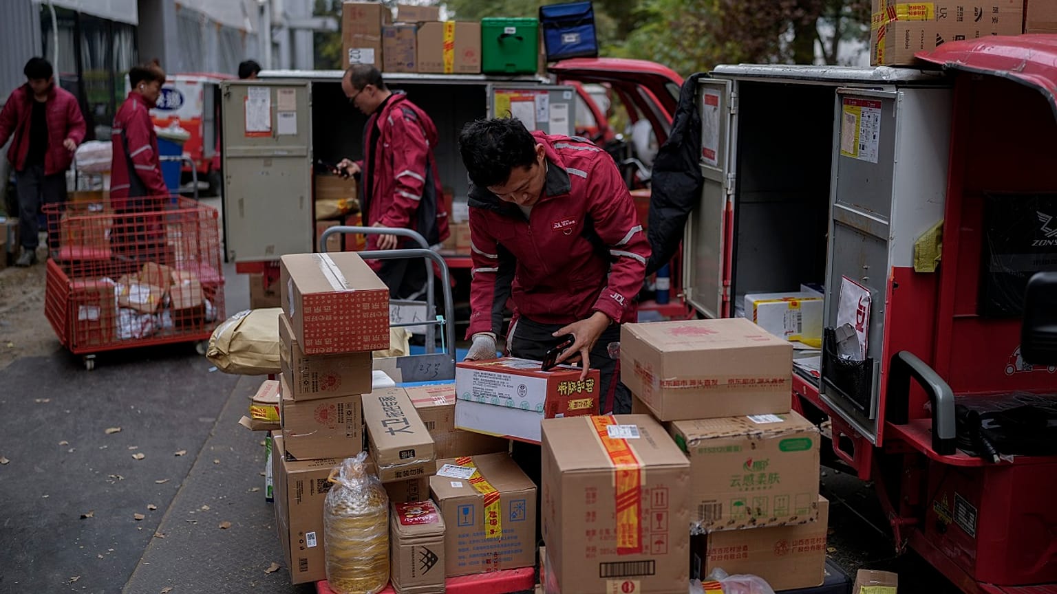 Los mensajeros de reparto clasifican los paquetes para sus clientes en un centro de distribución de una plataforma de comercio electrónico.