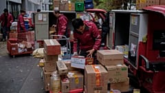 Los mensajeros de reparto clasifican los paquetes para sus clientes en un centro de distribución de una plataforma de comercio electrónico.