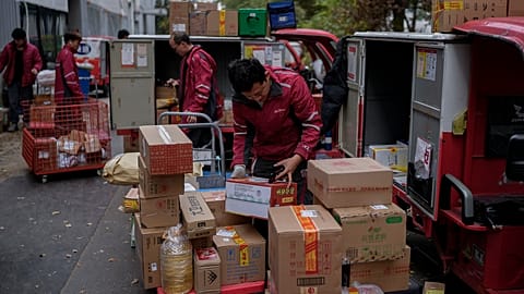 Delivery couriers sort out parcels for their customers at a distribution center for an e-commerce platform.