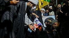 Manifestantes, incluindo clérigos, queimam a bandeira israelita situada na embaixada dos EUA em Bagdade, no Iraque, na segunda-feira, 16 de junho de 2025. 