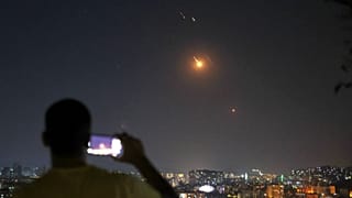 Un homme prend une photo avec son téléphone portable alors que des missiles tirés par l'Iran en direction d'Israël survolent le territoire syrien à Damas, en Syrie, mercredi 18 juin 2025.