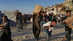 Palestyńczycy niosą worki i pudła z żywnością oraz pomocą humanitarną, rozładowaną z konwoju Światowego Programu Żywnościowego,