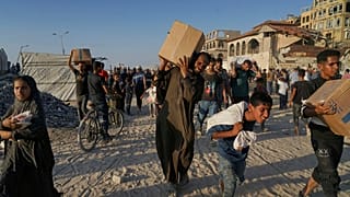 Palestyńczycy niosą worki i pudła z żywnością oraz pomocą humanitarną, rozładowaną z konwoju Światowego Programu Żywnościowego,