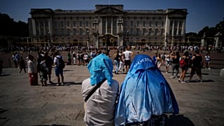 People cover their heads outside Buckingham Palace, during the heatwave in London on 18 July 2022.