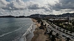 Turistas pasean por la orilla de la playa antes de la llegada del huracán Erick, en Acapulco, estado de Guerrero, México.
