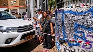 Eine Frau mit einem M16-Gewehr steht neben einem zerstörten Gebäude, das von einer aus dem Iran abgefeuerten Rakete getroffen wurde, in Holon, nahe Tel Aviv, Israel, am Donnerstag, den 19. Juni 2025.