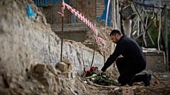 Der ukrainische Präsident Wolodymyr Selenskyj legt am 19. Juni Blumen an der Stelle nieder, an der ein tödlicher russischer Raketenangriff am Dienstag ein mehrstöckiges Wohngebäude in Kyjiw zerstört hat.