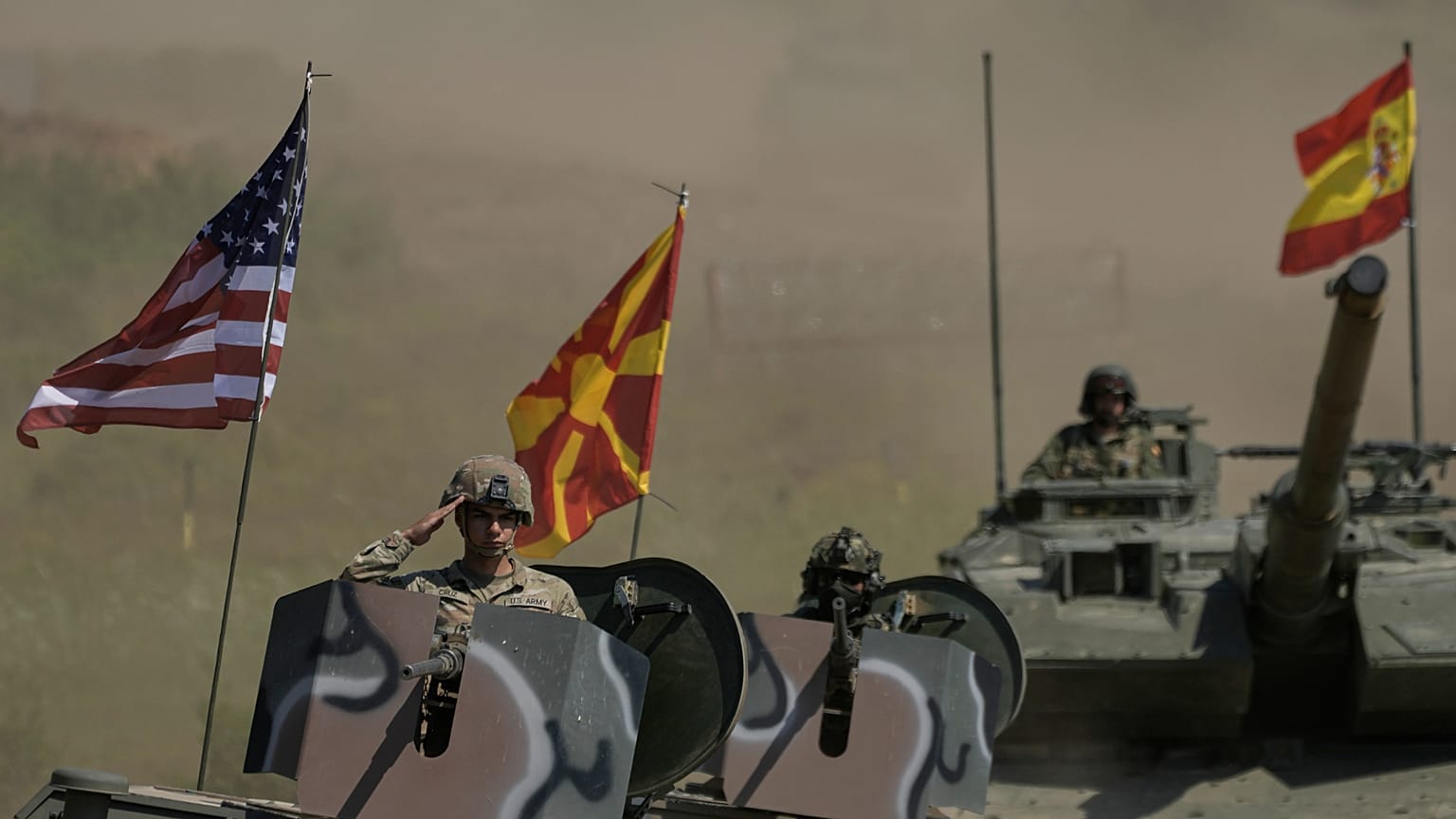 Żołnierz na czołgu salutuje, podczas gdy inne pojazdy z Macedonii Północnej i Hiszpanii podążają za nim podczas ćwiczeń wojskowych "Immediate Response 25", 4 czerwca 2025 r.
