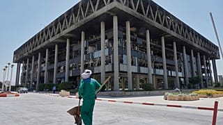 عامل يدحرج عربة يدوية أمام مقر إذاعة جمهورية إيران الإسلامية المتضرر في طهران، إيران، الخميس، 19 يونيو/حزيران 2025.