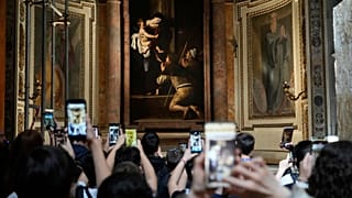 Tourists admire the Pilgrims' Madonna, by Caravaggio at the Basilica of St. Augustine in Rome.