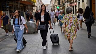Tourists carry their luggage in downtown Madrid, Spain, June 3, 2025. 
