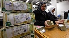 موظفون سوريون يكدسون رزمًا من العملة السورية في البنك المركزي السوري في دمشق، سوريا