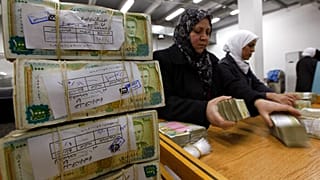 موظفون سوريون يكدسون رزمًا من العملة السورية في البنك المركزي السوري في دمشق، سوريا