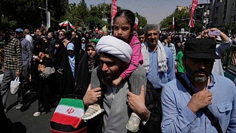 A cleric carries a small child on his shoulder during a demonstration to denounce Israeli attacks on several cities across Iran, after Friday prayers in Tehran, Iran, Friday, 20 June 2025