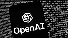 Das OpenAI-Logo erscheint auf einem Mobiltelefon vor einem Computerbildschirm mit binären Zufallsdaten, Donnerstag, 9. März 2023, in Boston