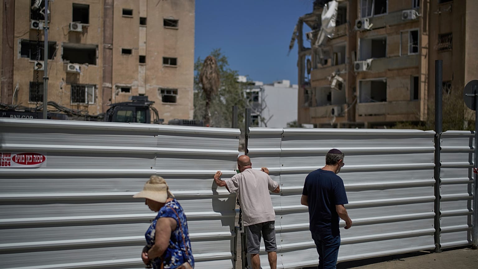 Bir adam, İran füzesinin Tel Aviv yakınlarındaki Holon’da bir yerleşim alanına düşmesinden bir gün sonra çitin üzerinden bakıyor, 20 Haziran 2025.