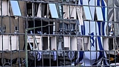 العلم الإسرائيلي ينعكس على نوافذ مبنى مدمر في رمات غان ، إسرائيل ، بعد يومين من إصابته بصاروخ أطلق من إيران ، السبت 21 يونيو / حزيران 2025.