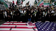 Des musulmans chiites se tiennent au-dessus d'une représentation du drapeau américain lors d'un rassemblement pour condamner les frappes israéliennes sur l'Iran, à Karachi, au Pakistan, le dimanche 22 juin 2025.