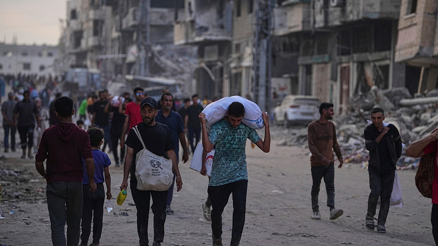 فلسطينيون يحملون أكياسا غذائية ومساعدات إنسانية تم تفريغها من قافلة شاحنات كانت متوجهة إلى مدينة غزة ، شمال قطاع غزة ، الأحد 22 حزيران / يونيو 2025.