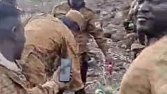 Des hommes en uniforme militaire du Burkina Faso entourent un cadavre allongé sur le sol dans une image tirée d'une vidéo publiée par un groupe Telegram affilié au groupe Wagner.