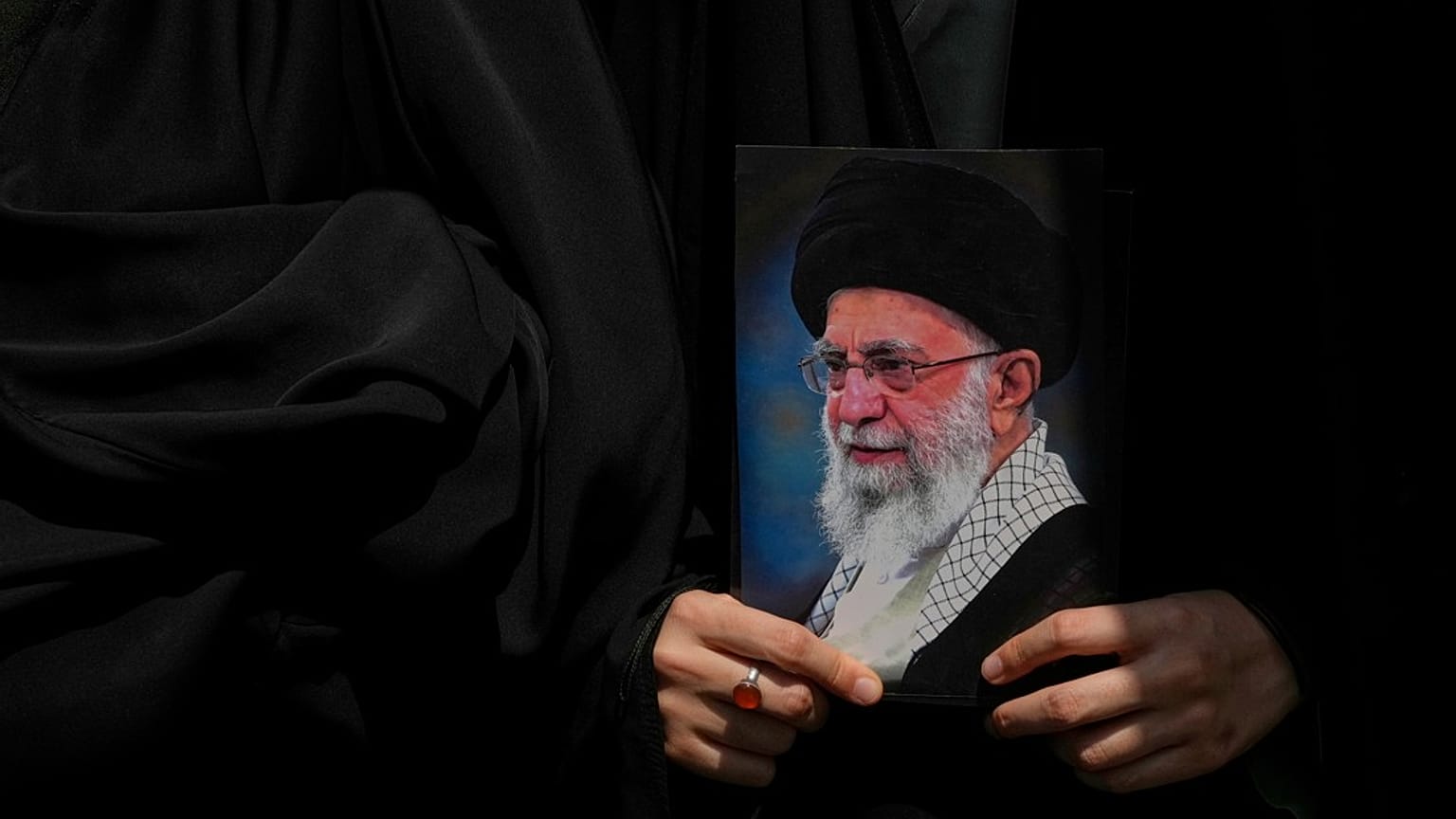 متظاهر يحمل ملصقًا للمرشد الأعلى الإيراني آية الله علي خامنئي، إيران، الجمعة 20 يونيو 2025.  