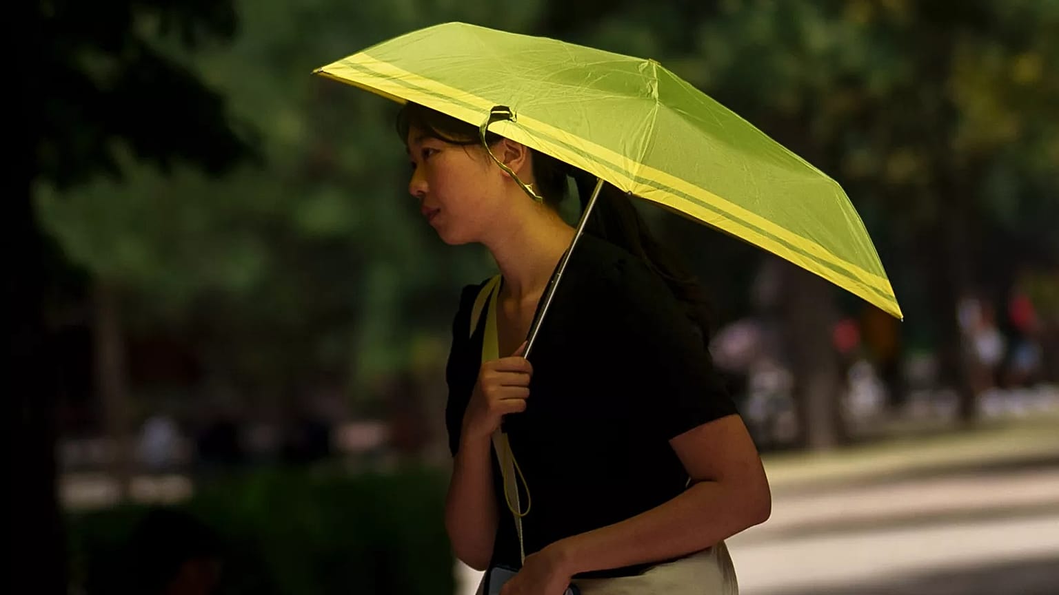 Una donna si ripara dal sole nel parco del Retiro a Madrid, in Spagna, luglio 2023