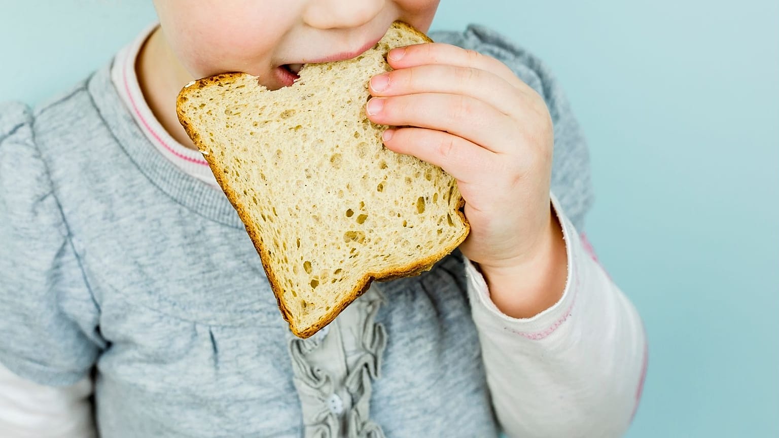 Un niño se come una rebanada de pan.
