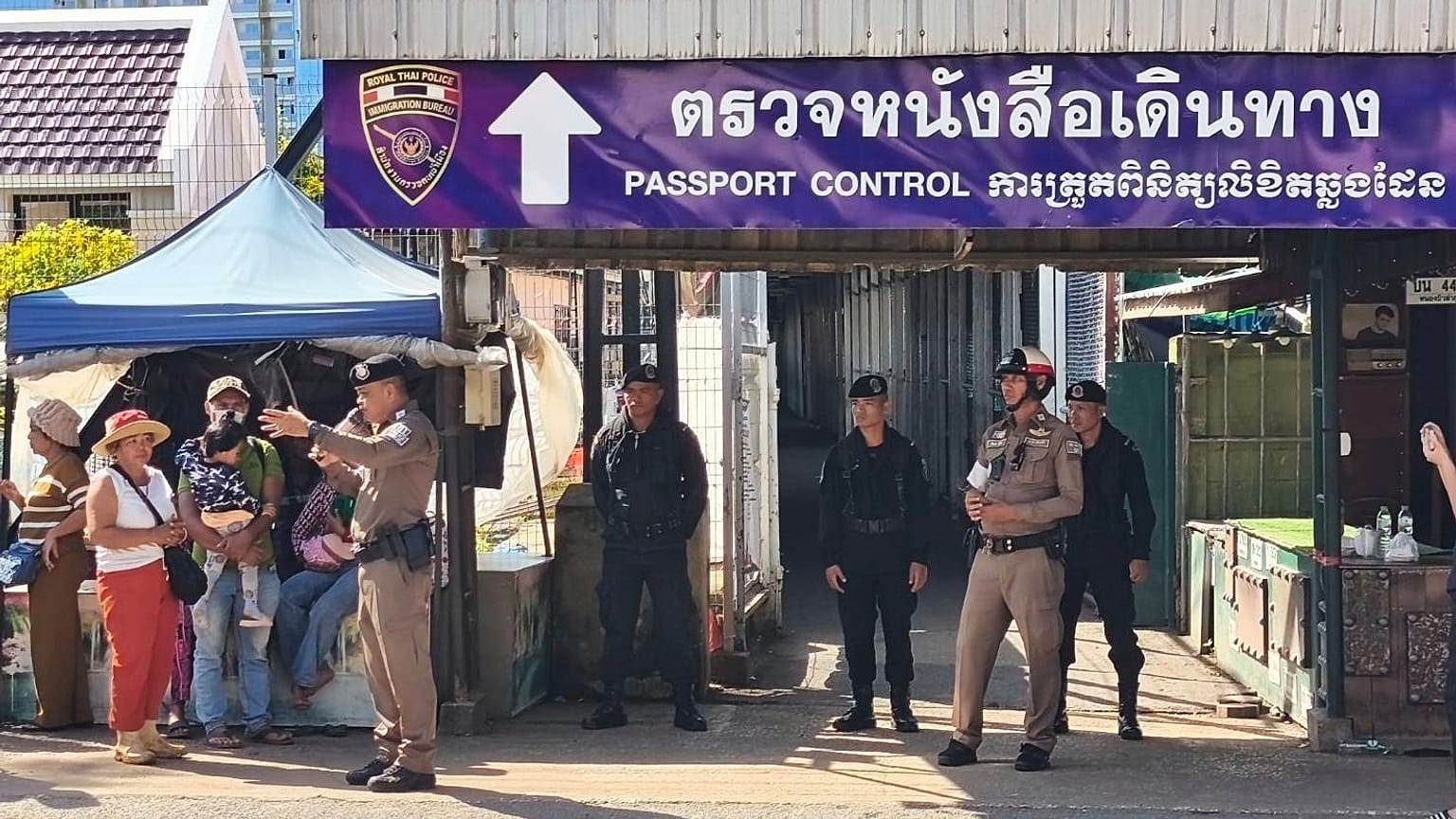 Un agente de policía tailandés habla con la gente cerca de un puesto de control fronterizo entre Tailandia y Camboya, en la provincia tailandesa de Sa Kaeo, 24 de junio de 2025.