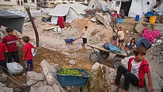 شباب وأطفال فلسطينيون في مخيم أقيم وسط البنية التحتية المتضررة من الحرب في مدينة غزة، يوم الاثنين 23 يونيو/حزيران 2025. 