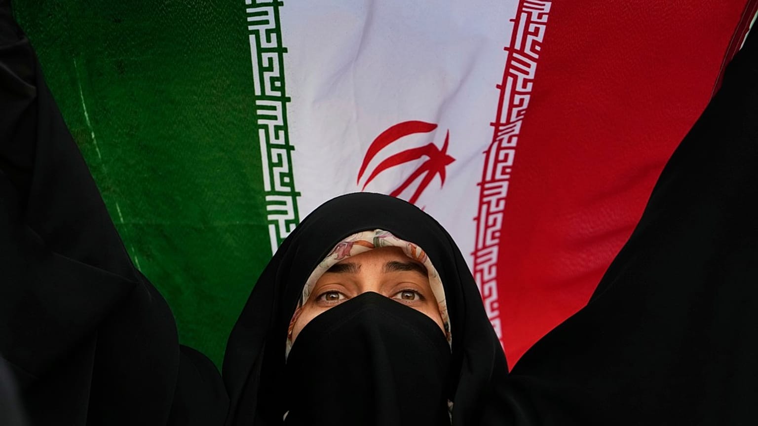 امرأة إيرانية ترفع علم بلادها في مظاهرة مناهضة للولايات المتحدة وإسرائيل، إيران، الثلاثاء 24 يونيو/حزيران 2025.  